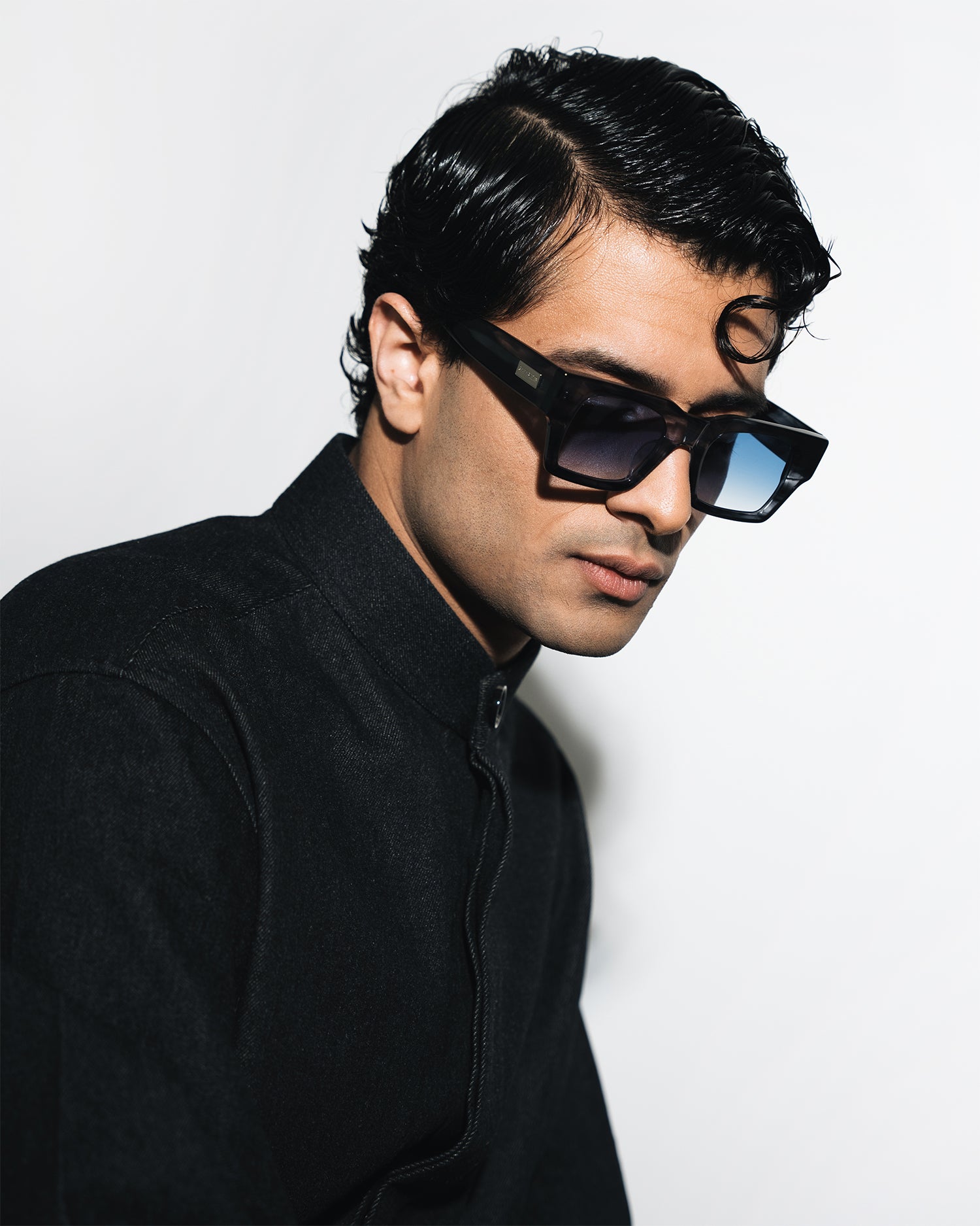 Man wearing sunglasses and a black outfit against a white background